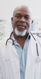 Vertical video of portrait of happy african american male doctor. Global medicine, health, lifestyle and hospital concept.
