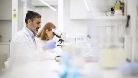 Man and woman laboratory technicians intently work with microscopes, analyzing samples in a scientific study, showcasing teamwork in research - Powered by Shutterstock - Get 15% off with code: PIKWIZARD15