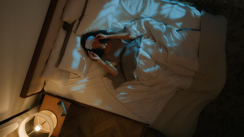 Top view African American woman tired falling on comfortable bed soft pillow cozy mattress sleepy girl put on sleeping mask fall asleep night dreams sleep napping nap in evening home bedroom relaxing