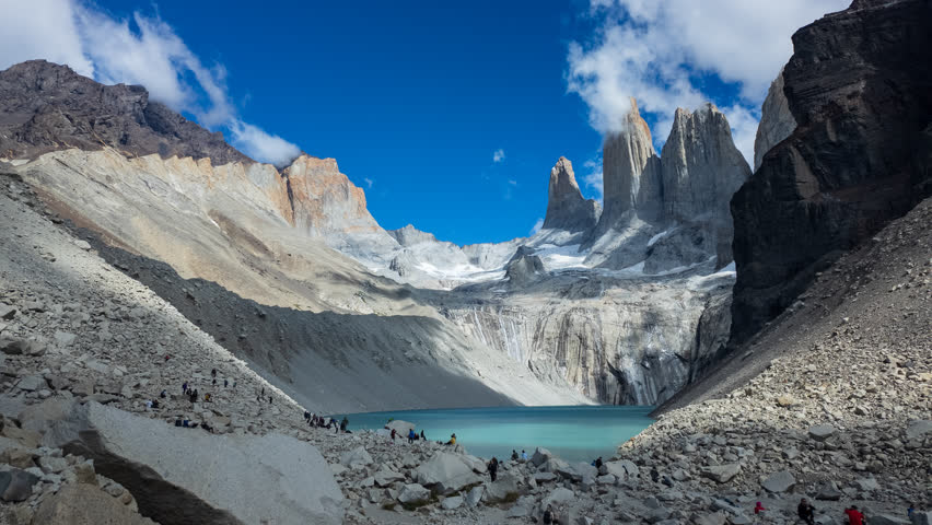 A timelapse shows people at Torres del Paine with clouds over mountains and a glacial lake.