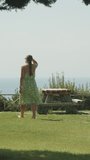 A park by the sea, a bench by the cliff, a young woman goes to the table Vertical video Social Media