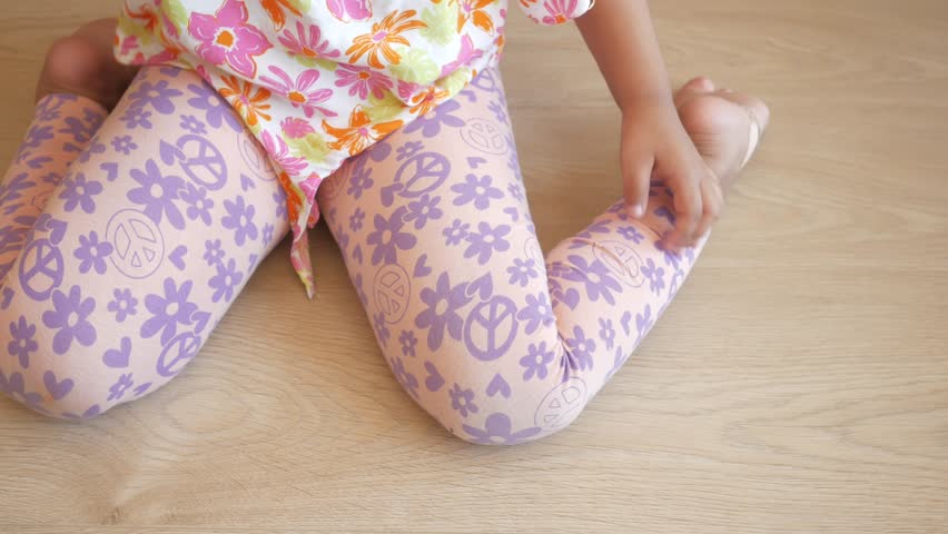  child sitting W posture on the floor .