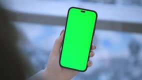 Back view of brunette holding chroma key green screen smartphone watching content. Shopping online. Gadgets and contemporary people concept. 4K - Powered by Shutterstock - Get 15% off with code: PIKWIZARD15