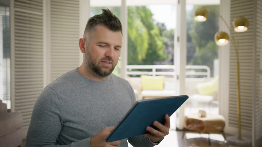 Winner concept. Smiling man looking at tablet screen and screaming in excitement. Overjoyed middle age male browsing online on tablet. Handsome guy using modern technology for leisure at home 4K Royalty-Free Stock Footage #3457689685