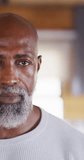 Vertical video of portrait of happy senior african american man spending time in log cabin. Free time, domestic life and nature concept.