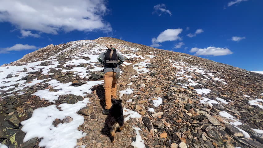 Hiker with dog on Mount Lincoln loop Kite Lake Trail hiking 14er Rocky Mountains Colorado dusting Bross Cameron Democrat Grays Torreys Quandary peaks fall first snow dusting blue sky follow