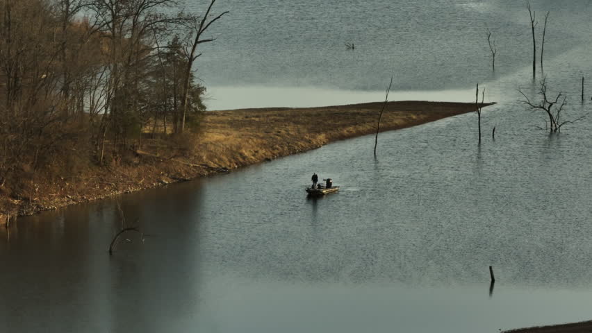 Two people fishing from a boat on Lake Flint Creek near Lake Swepco, Arkansas, on an overcast day