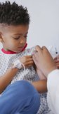 Vertical video of african american male doctor vaccinating child patient at hospital. Medicine, healthcare, lifestyle and hospital concept.