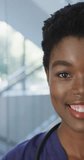 Vertical video of portrait of african american female doctor smiling at hospital. Medicine, healthcare, lifestyle and hospital concept.