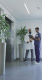 Vertical video of african american male and female doctors talking at hospital. Medicine, healthcare, lifestyle and hospital concept.