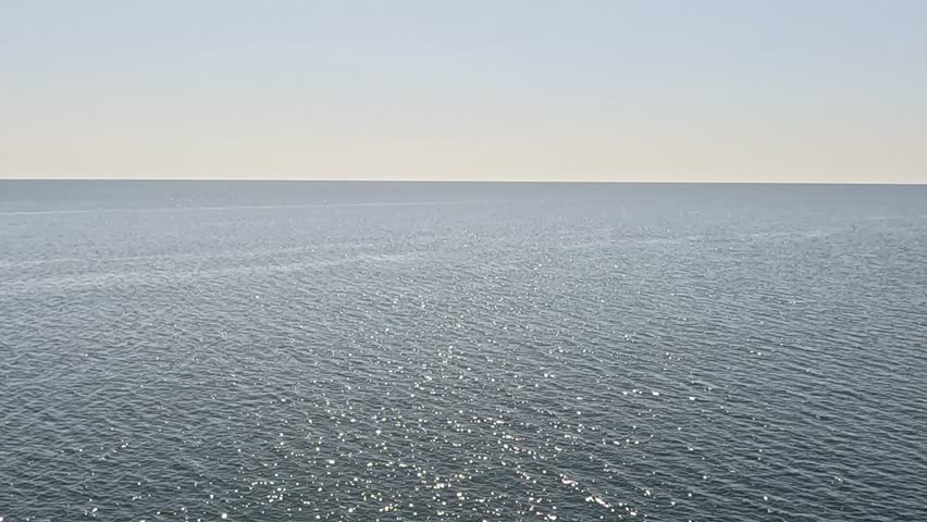 Sea water surface. Aerial view over clear azure sea water. Sun glare. Abstract nautical summer ocean nature. Holiday, vacation and travel concept. Nobody. Slow motion. Weather and climate change