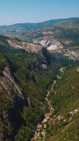 Marvelous rocky landscape on sunny clear daytime. Pine trees growing on the mountains of Yosemite National Park, United States, USA from top. Vertical video.