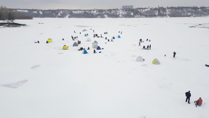Aerial view over frozen winter lake with lots of tents popular for fishing.