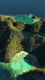 Aerial view of tropical Coron island in Philippines. Blue lagoons and lakes, white sand beach, rocks cliffs mountains and beautiful coral reef. Vertical video