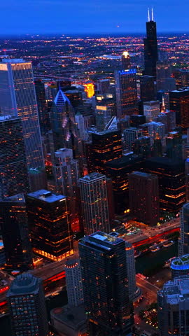 Breath-taking view of Chicago cityscape full of evening lights at dusk. Amazing metropolis at foreground. Aerial perspective. Vertical video.