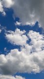 Cloudscape building in the blue sky. Soft puffy clouds flying quickly. Low angle perspective. Timelapse. Vertical video.