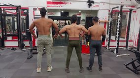 Three muscular men showing off their back muscles inside a gym motivation video for gym Asia india