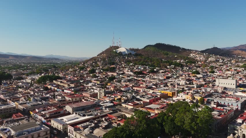 Drone shot over Oaxaca City during the day. Shot moves forward and slowly elevates.