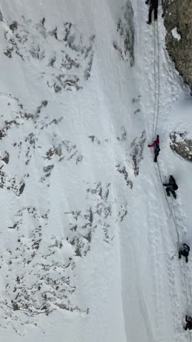 Aerial view of a group of mountaineers tied with climbing rope are climbing on a snowy slope. Royalty-Free Stock Footage #3458108713