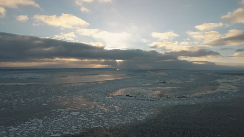 Polar sunrise over Antarctic coast. Ocean covered ice. Top above aerial view. Antarctica snow mountain. Sky sunrise Antarctica winter. Open water. Beautiful sky landscape. Top Drone Flight