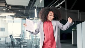 Happy joyful young african american female employee dancing victory dance in corridor or hall of modern business center. Funny excited black woman office worker cheerfully celebrating achievement - Powered by Shutterstock - Get 15% off with code: PIKWIZARD15