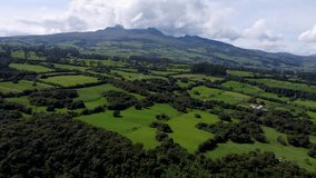 Cinematic drone clp flying up high over a large area covered with green and fields in Puichig, Equador