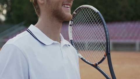 Close-up of smiling tennis player throwing yellow ball, preparing for game