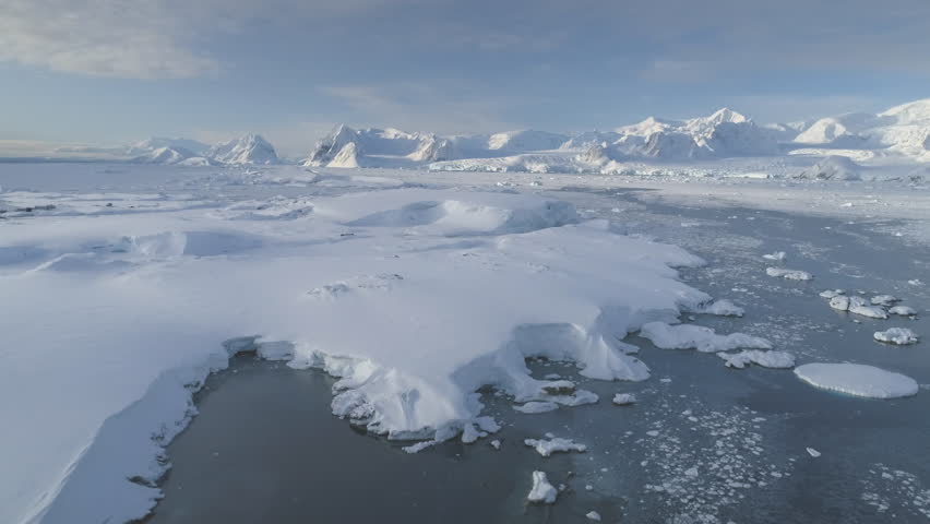 White glacier on Antarctic Peninsula. Aerial shot close-up. Antarctica panoramic drone flight view. Snow among polar ice. Cave in iceberg around frozen water. Permafrost. Antarctic continent.