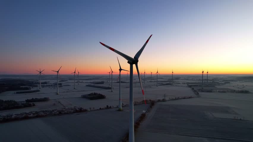 Köhlen - Northern Germany - large wind turbines in the wind farm in the icy sunrise in the North German lowlands on slightly frozen fields rotate slowly and majestically Royalty-Free Stock Footage #3458192525