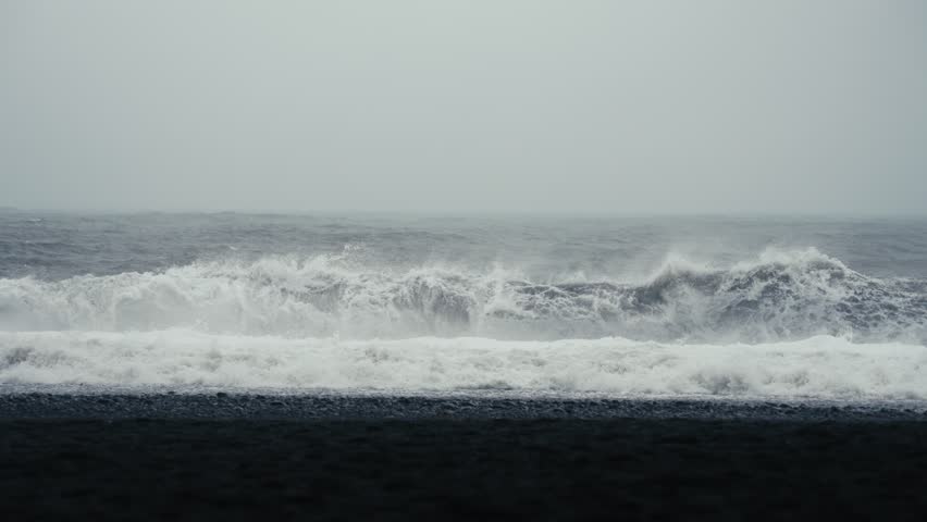 Dark majestic waves crash onto a black sand beach. Reynisfjara Iceland. Shot in glorious slow motion. Royalty-Free Stock Footage #3458207725
