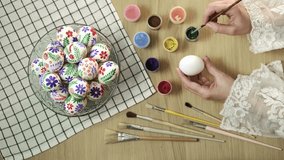 Process of making handmade painted Easter eggs. Close-up of hands painting Easter egg with paint and brush. Preparing for Easter, Christian tradition Vertical video