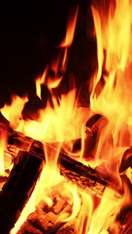Wood is burning in the fireplace. Fire in the oven. The burning logs. Furnace heating. A fire burns in a fireplace. Christmas Holidays Concept. Video for Meditation Vertical video