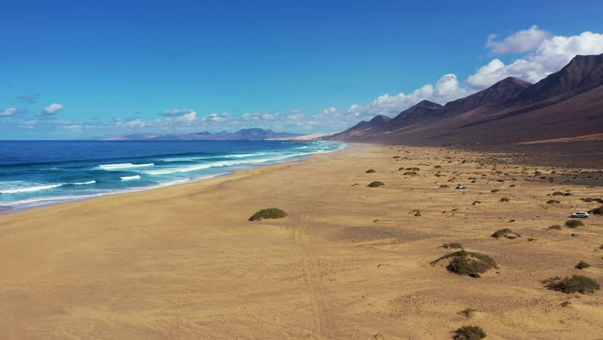 Amazing Cofete beach with endless horizon. Volcanic hills in the background and Atlantic Ocean. Cofete beach, Fuerteventura, Canary Islands, Spain. Playa de Cofete, Fuerteventura, Canary Islands.