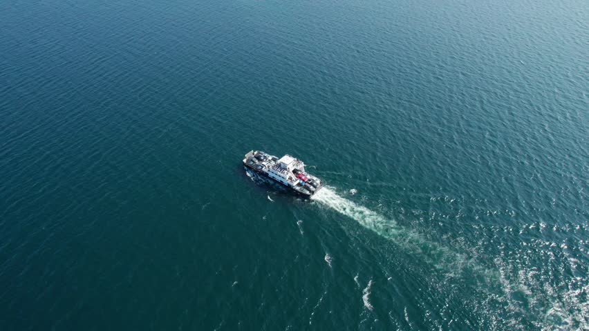 Drone view looking down on a ferry traveling with cars and people to an island