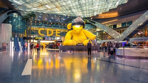 Doha, Qatar, 3 January 2018. Hamad International Airport in Doha, departure hall with a sculpture, often known as "Lamp Bear". Blurred crowd of people. Time lapse. Zoom effect