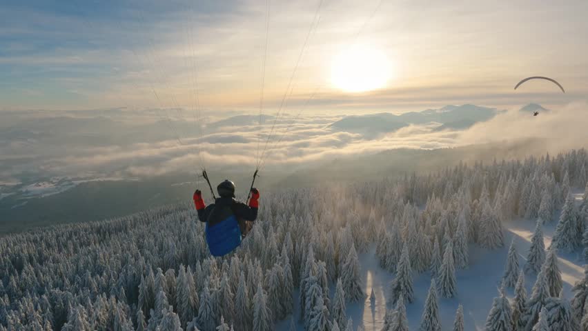 Peaceful evening paragliding flying above frozen forest in winter wonderland nature, Adrenaline outdoor adventure