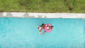 An African American family floats on a pink inflatable ring in a pool at home. They enjoy a sunny day, with the family members embracing in a protective manner. - Powered by Shutterstock - Get 15% off with code: PIKWIZARD15