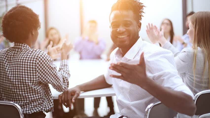 a black man posing for the camera in front of his colleagues clapping his hands Royalty-Free Stock Footage #3458456449