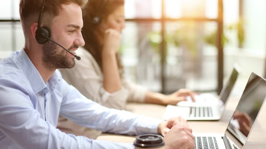Guy from technical customer service support answering voice calls from clients in office