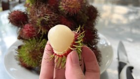 Hands showing an effective way to open an exotic. tropical rambutan fruit. Close up. Video 4k. High quality 4k footage