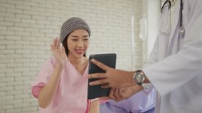 Happy young asian woman patient talking via video call with family while being treated at the hospital. Woman patient waving hand while talking virtual online with family on tablet