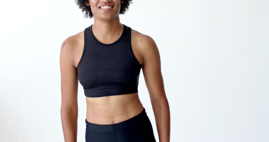 Biracial woman with curly black hair laughs joyfully, wearing a black tank top. Her bright expression and casual attire suggest a relaxed and happy moment, slow motion.