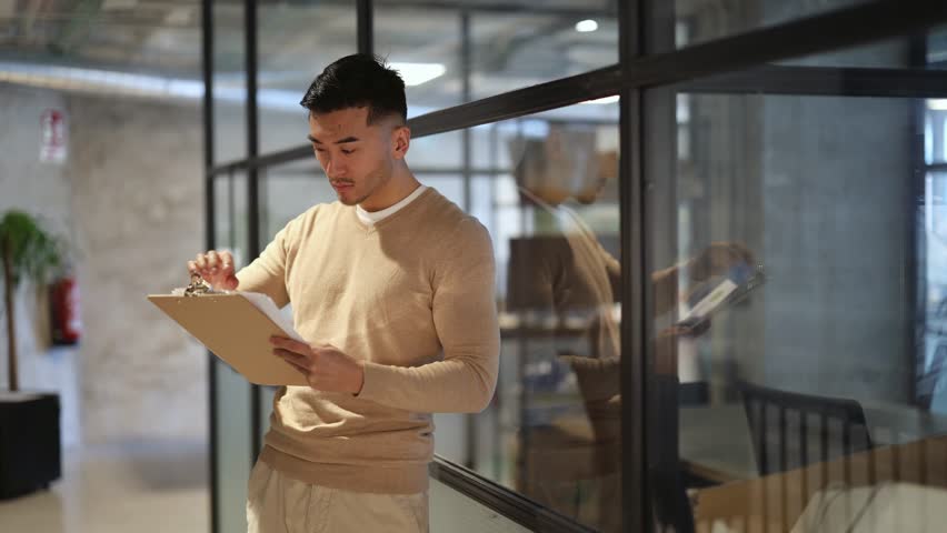 Confident businessman in a modern office extends a welcoming handshake. Smiling Asian businessman extending handshake in office