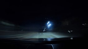 Motion timelapse of a speedy night drive in a big city. Front view from the car window to the road with light trails from vehicles and street lights.