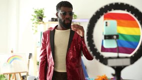handsome and happy young adult african american man in sequin blazer records himself dancing live for social media before pride party - LGBTQ concept