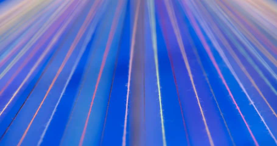 Converging Multi-colored Sewing Thread on a rotating table, blue background