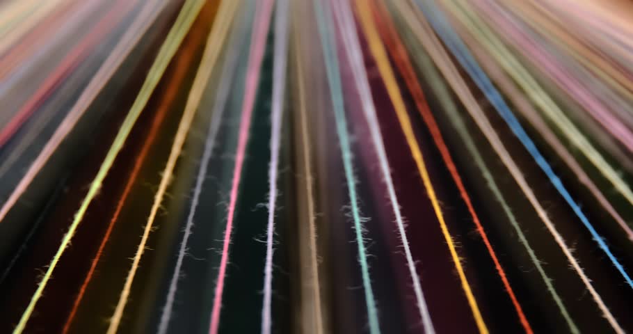 Converging Multi-colored Sewing Thread on a rotating table, dark background