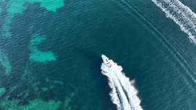 Aerial view of speedboat floating in the Aegean sea on a sunny day. Fast boat on sea surface. Sea view from drone. Travel video by yatch