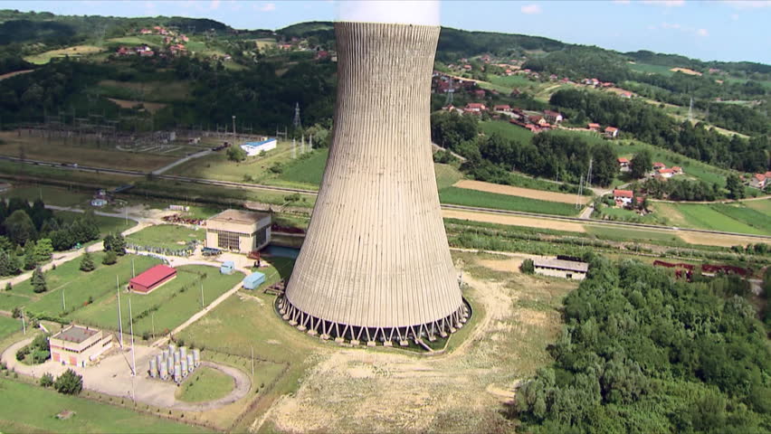 A Power Plant and its cooling tower with steam rising from it and tall flue gas