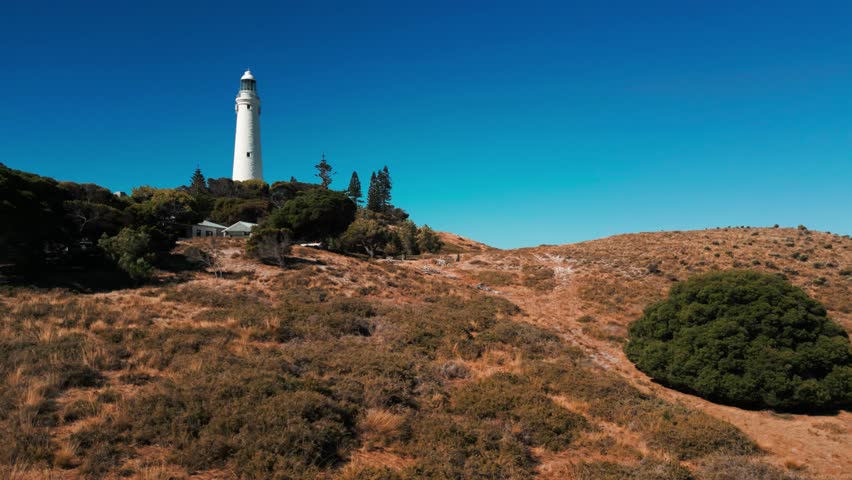 drone shot over wadjemup lighthouse on Rottnest Island on a sunny day revealing the seashore behind. Western Australia